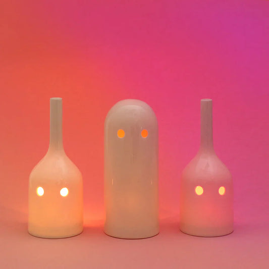 Three ghost-shaped lamps with glowing eyes on a pink and red gradient background