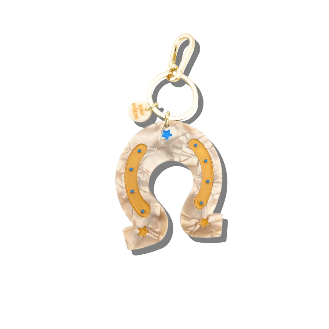 Horseshoe-shaped pendant with gold accents on a white background. Add some charm to your keys with these Hand-Painted Keychains, crafted from eco-friendly cellulose acetate. Featuring design on both sides and packaged in premium, plastic-free materials. Quirky, stylish, and environmentally friendly.