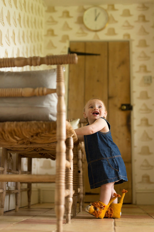 Child standing on a wooden floor with a wool lion slippers