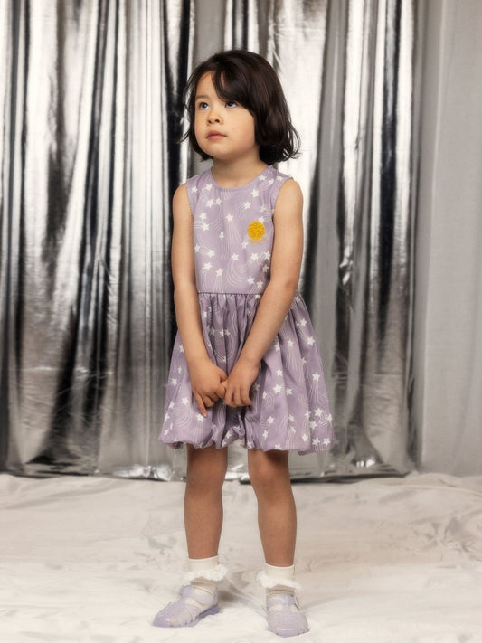 Sleeveless dress made from 100% lyocell. Features the Starfall print, a gathered skirt with bubble hem, and a small embroidered planet patch. Back neck keyhole with snap closure.