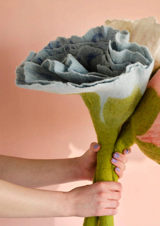 Bouquet of fabric flowers held by a person against a pink background