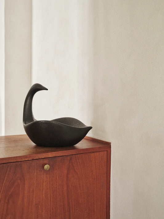 Black goose-shaped sculpture on a wooden surface with a neutral background