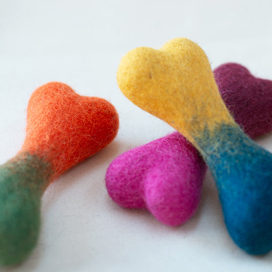 Colorful bone-shaped felt toys on a white background