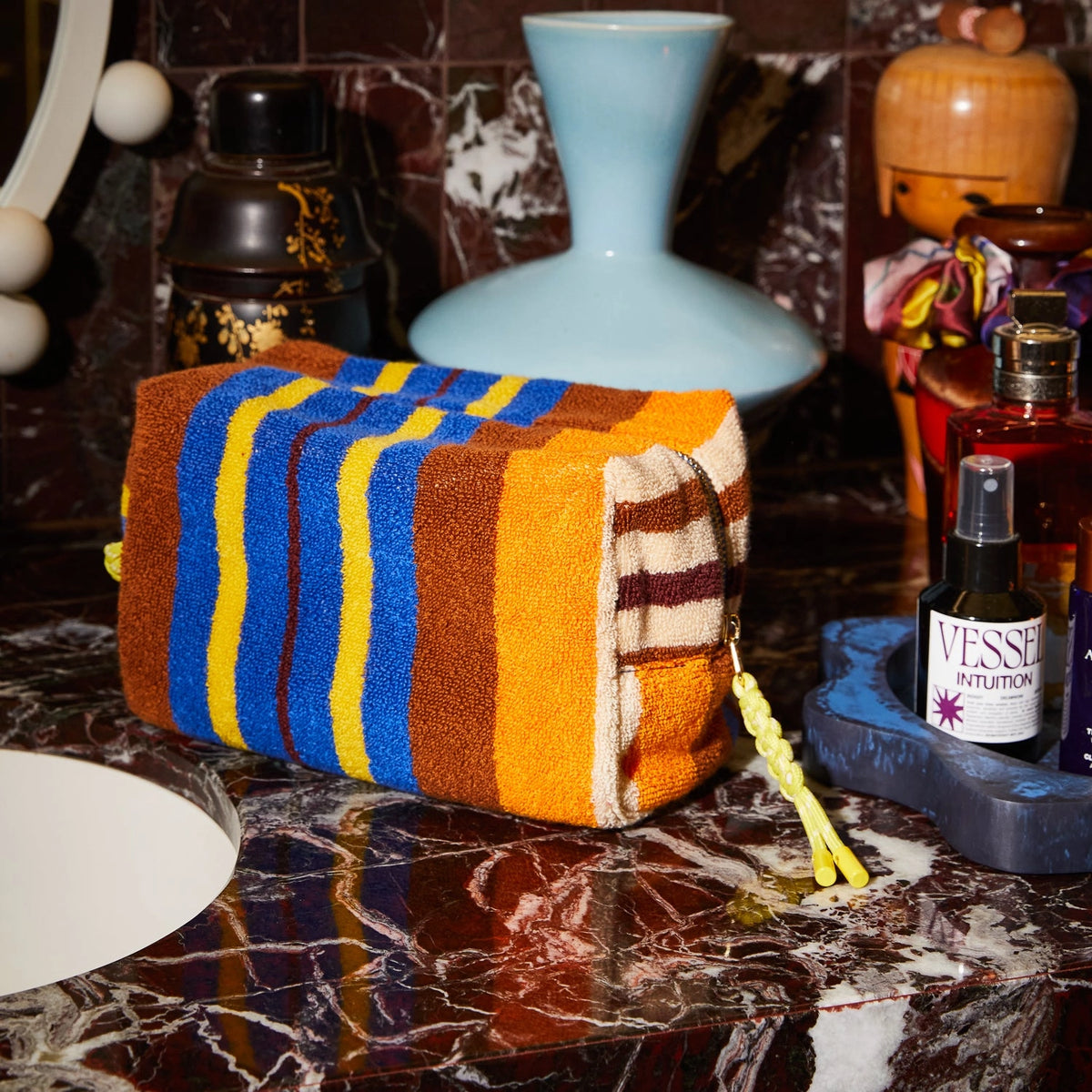 Colorful striped towel on a marble surface with decorative items in the background
