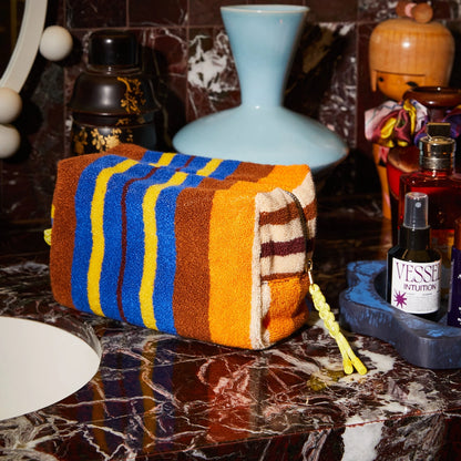 Colorful striped towel on a marble surface with decorative items in the background