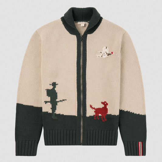 A beige and dark green knit zip-up cardigan sweater with a high ribbed collar, featuring a cowboy silhouette, a red dog, and a white dog graphic on the front, shown against a light gray background.