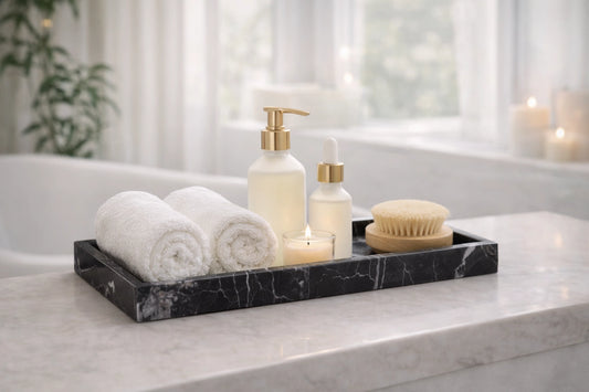 Bathroom scene with towels, bottles, and a candle on a marble tray.
