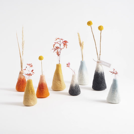 Set of small, colorful cone-shaped vases with dried plants on a white background