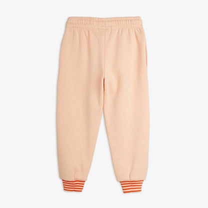 A pair of children's sweatpants in a soft peach color, featuring an elastic waistband and striped cuffs in orange and white.