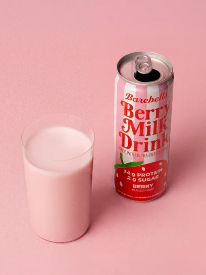Barebells Berry Milk Drink can and glass on a pink background