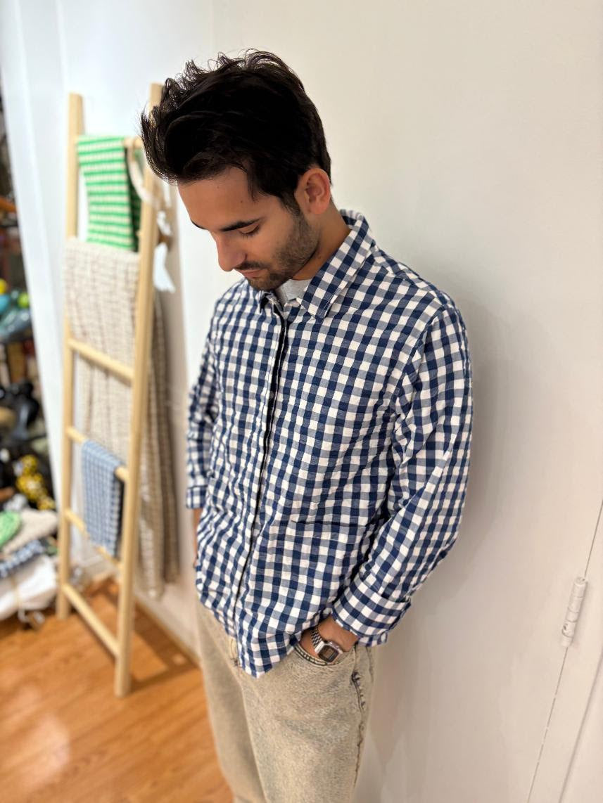 Man wearing a Danish blue and white checkered shirt. This stylish loungewear takes you from indoor to outdoor and day to night. Made of 100% cotton these Danish fashion pieces will feel amazing and make your hot days cooler. They have a pleasantly loose fit and comfortable cut, making them a versatile addition to your wardrobe. The Bæk&amp;Bølge series employs the classic seersucker weaving method, resulting in delectably soft, light-as-a-feather bedding and lounge wear.