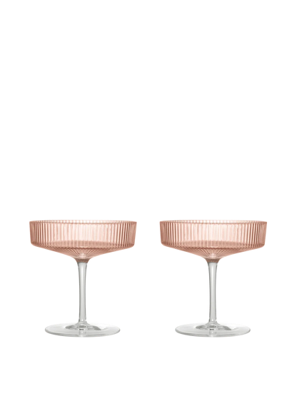 Two champagne coupe glasses with a ribbed, blush pink translucent bowl and clear glass stems, set against a solid white background.