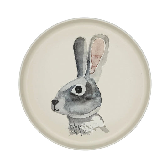 A round ceramic plate with a hand-painted watercolor rabbit illustration in gray, black, and soft pink on an off-white background.