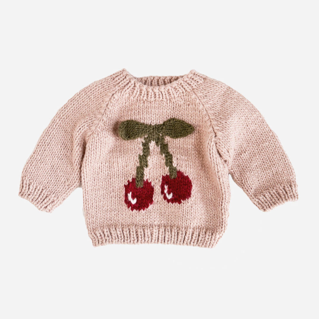 Add a pop of cherry red with this blush pullover features a pair of cherries with knitted appliqué 3-D leaves in a cozy moss color. The design is perfect for the first day of school or a night time walk. The way it looks hanging on a hangar also makes this such a cute piece of decor to hang in your child's room.