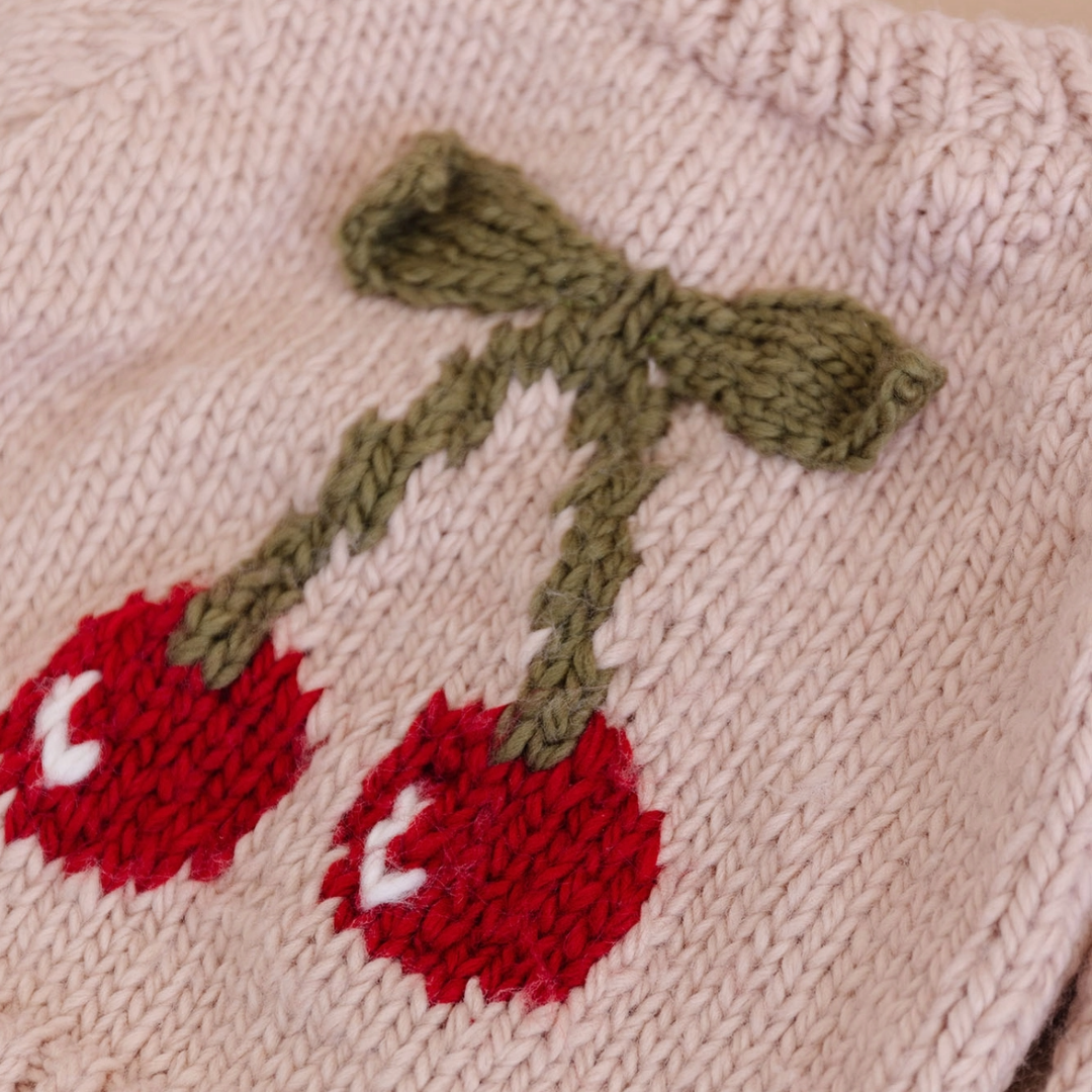Add a pop of cherry red with this blush pullover features a pair of cherries with knitted appliqué 3-D leaves in a cozy moss color. The design is perfect for the first day of school or a night time walk. The way it looks hanging on a hangar also makes this such a cute piece of decor to hang in your child's room.