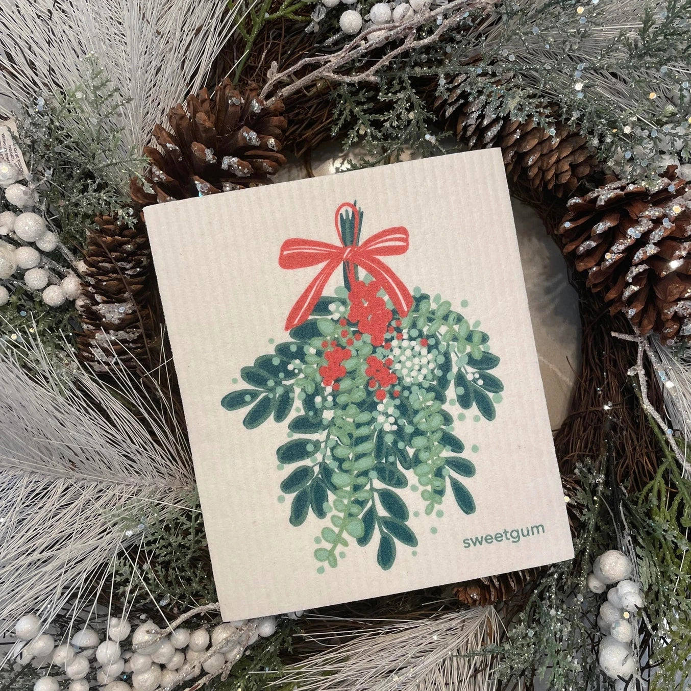 Mistletoe design swedish dishcloth with a Christmas design surrounded by festive greenery and pinecones