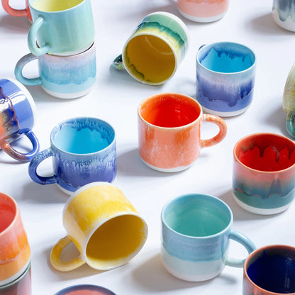 Colorful ceramic mugs on a white surface