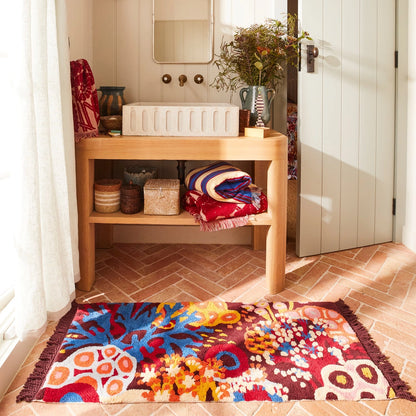 Colorful rug on a tiled floor in front of a wooden shelf with decorative items.
