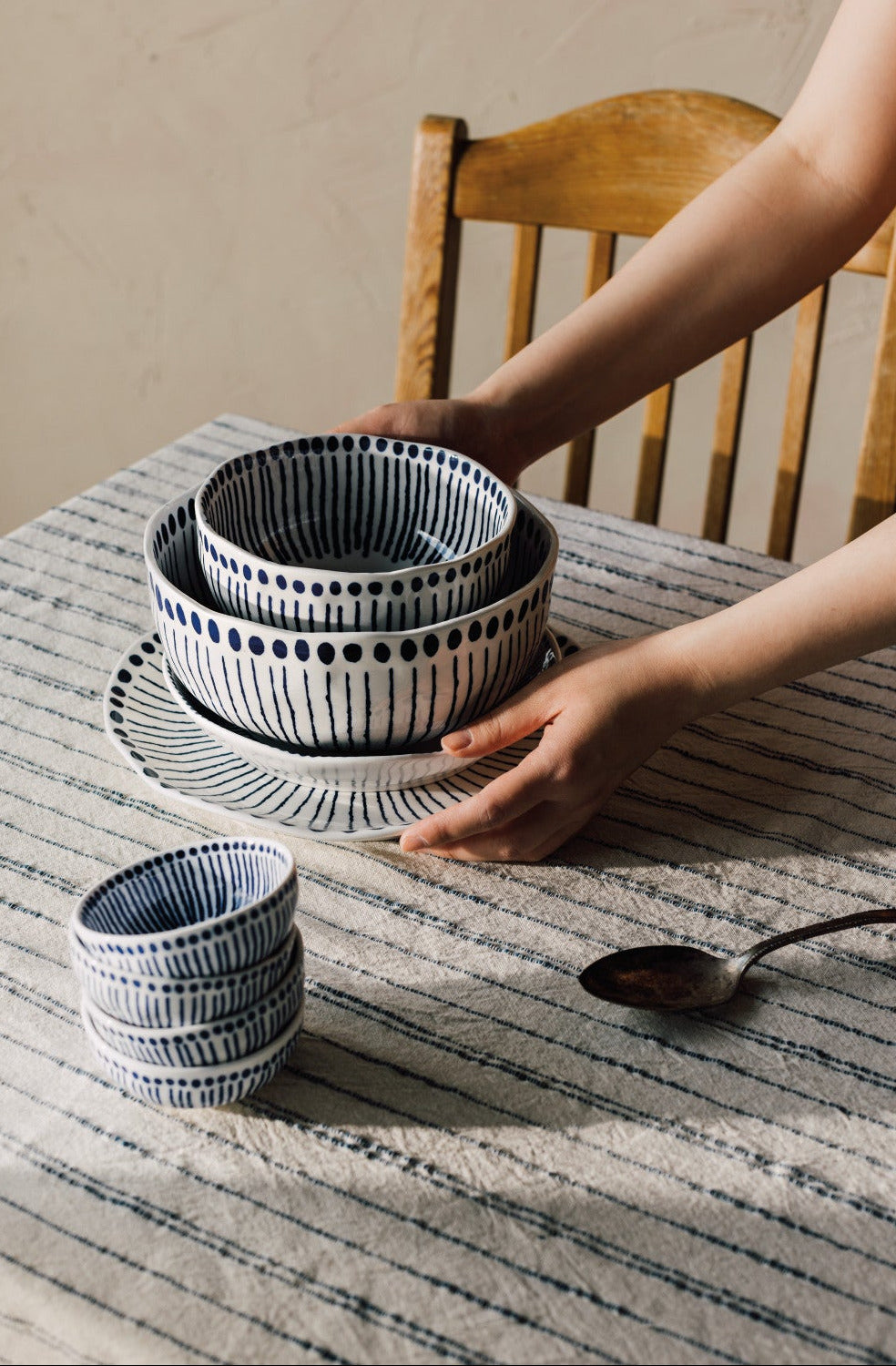 Set of navy and white patterned ceramic bowls on a table with a person's hand reaching towards them.