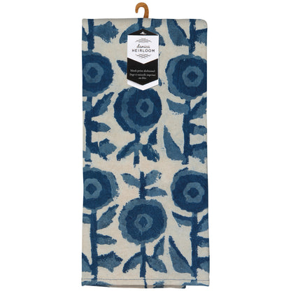 A linen kitchen towel with a blue floral block print on an off-white background, hanging from a wooden hanger with a 'Lana Heirloom' paper tag attached.