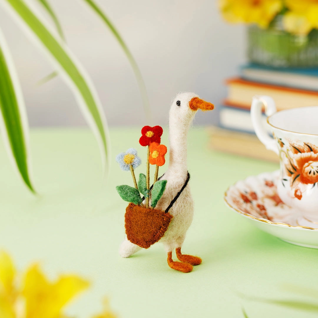 Decorative felt goose holding flowers on a table with a teacup and books in the background. Daphne loves growing summer blooms and giving them to her ducky friends!

Why not Send Daphne with a a loving bouquet to your special friend? She’s a tiny keepsake for all best friends 