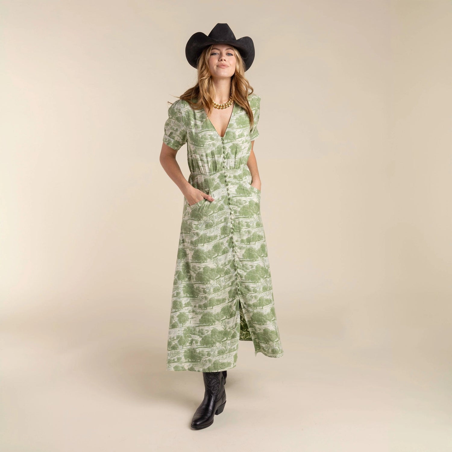 Woman wearing a green patterned dress and black cowboy hat and the Darcy Dress with feminine charm and a hint of retro style. Stylish dress 