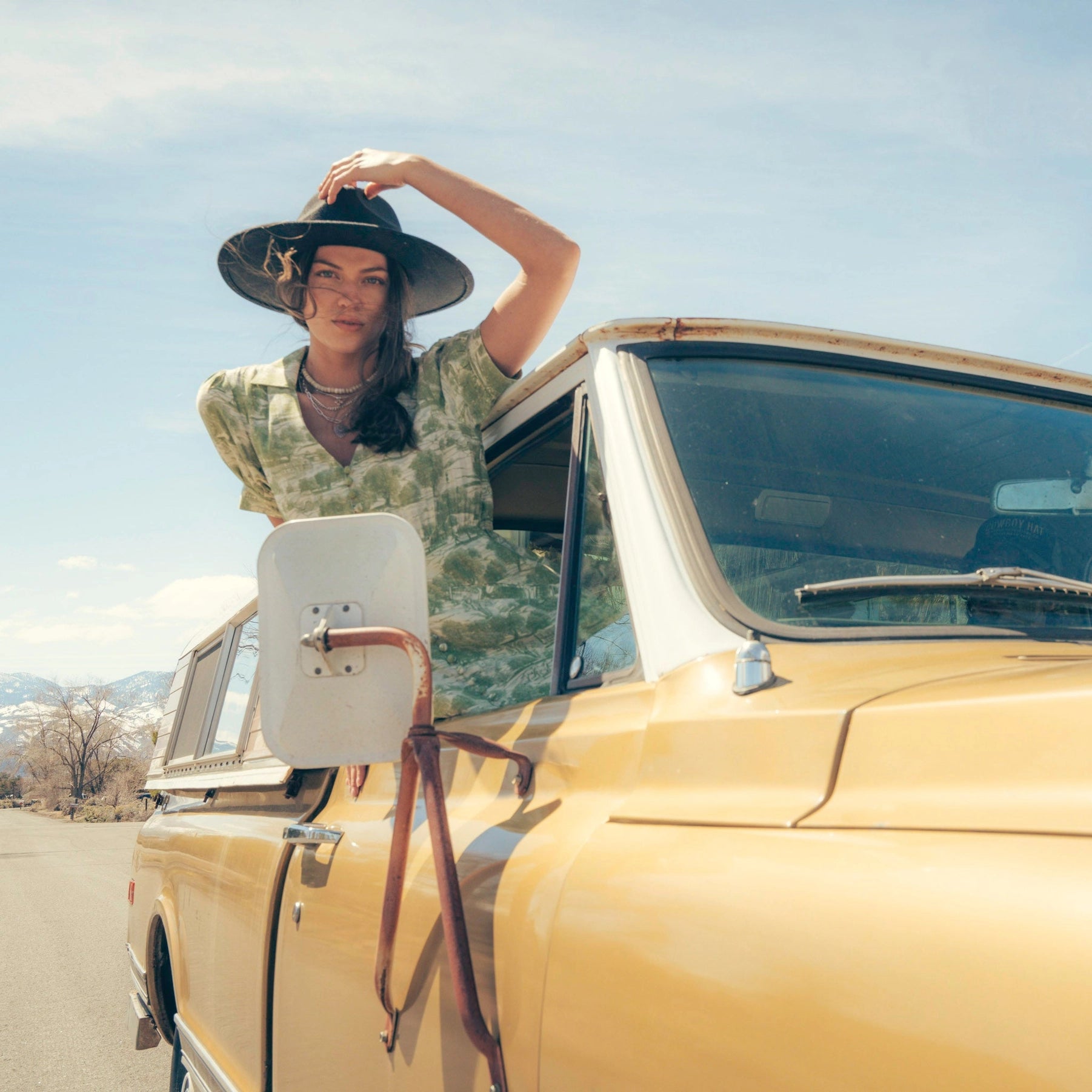 The Darcy Dress with feminine charm and a hint of retro style. Stylish dress cowboy rancher girl leaning out a old car window photo shoot, wild western