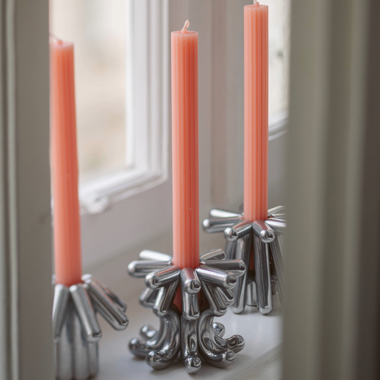 Silver candle holders by Form Follows with pink candles on a windowsill. Find them at Huset Shop on Abbot Kinney Boulevard in Venice California. Scandinavian Decor Shop with Scandinavian Candy 