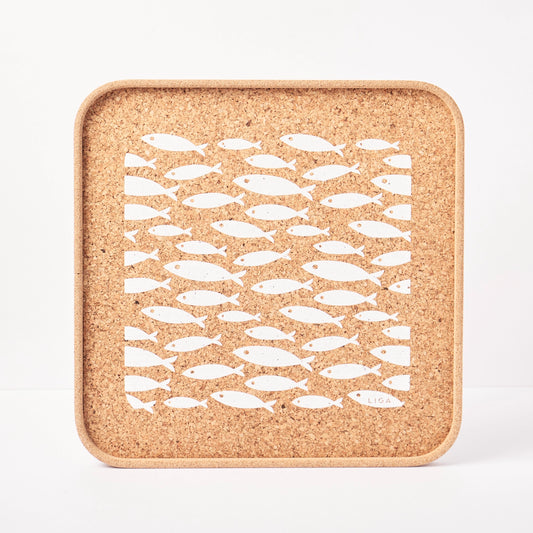 Cork trivet with white fish pattern on a white background