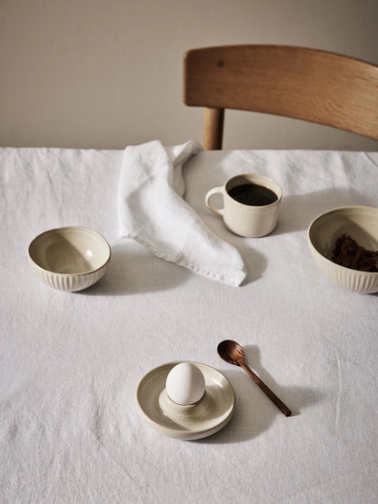 Egg Cup with a wooden spoon on beige table cloth
