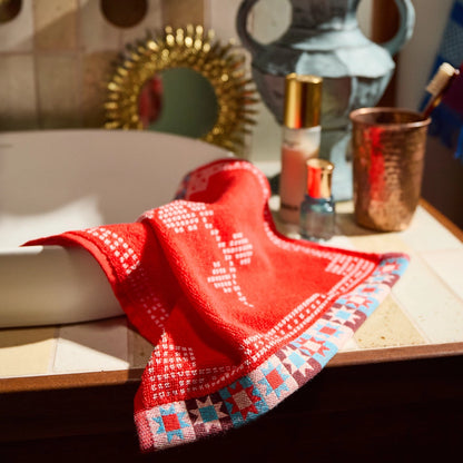 Red patterned small face towel hanging off sink in bathroom