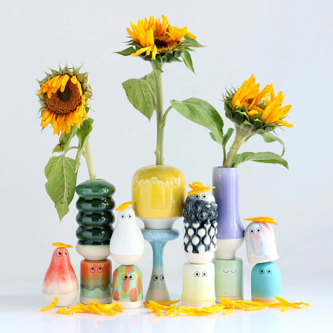 Colorful ceramic birds and vases with sunflowers on a light background