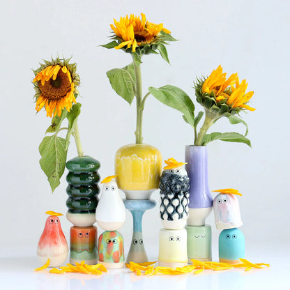 Colorful ceramic birds and vases with sunflowers on a light background