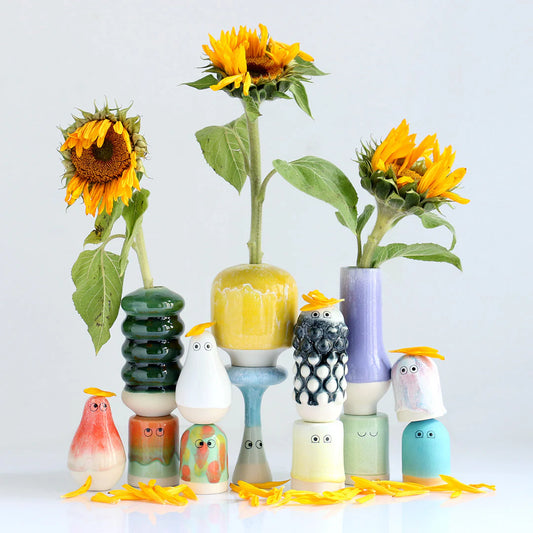Colorful ceramic birds and vases with sunflowers on a light background