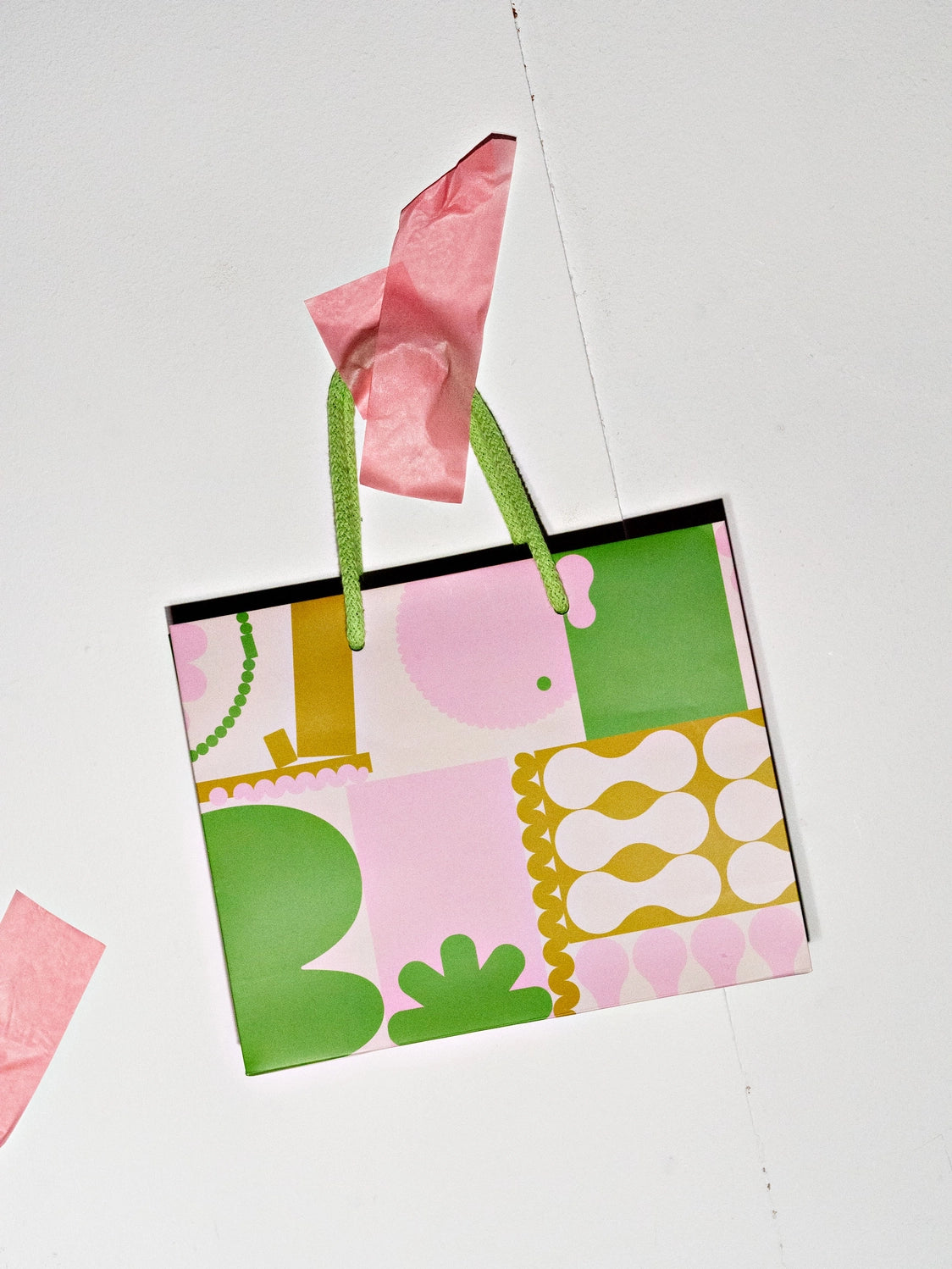 Colorful patterned gift bag with pink and green accents on a white background