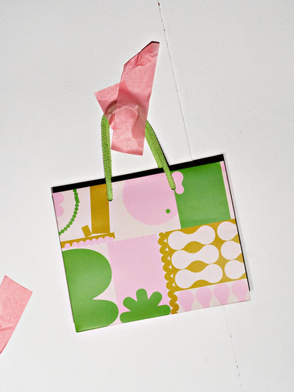 Colorful patterned gift bag with pink and green accents on a white background