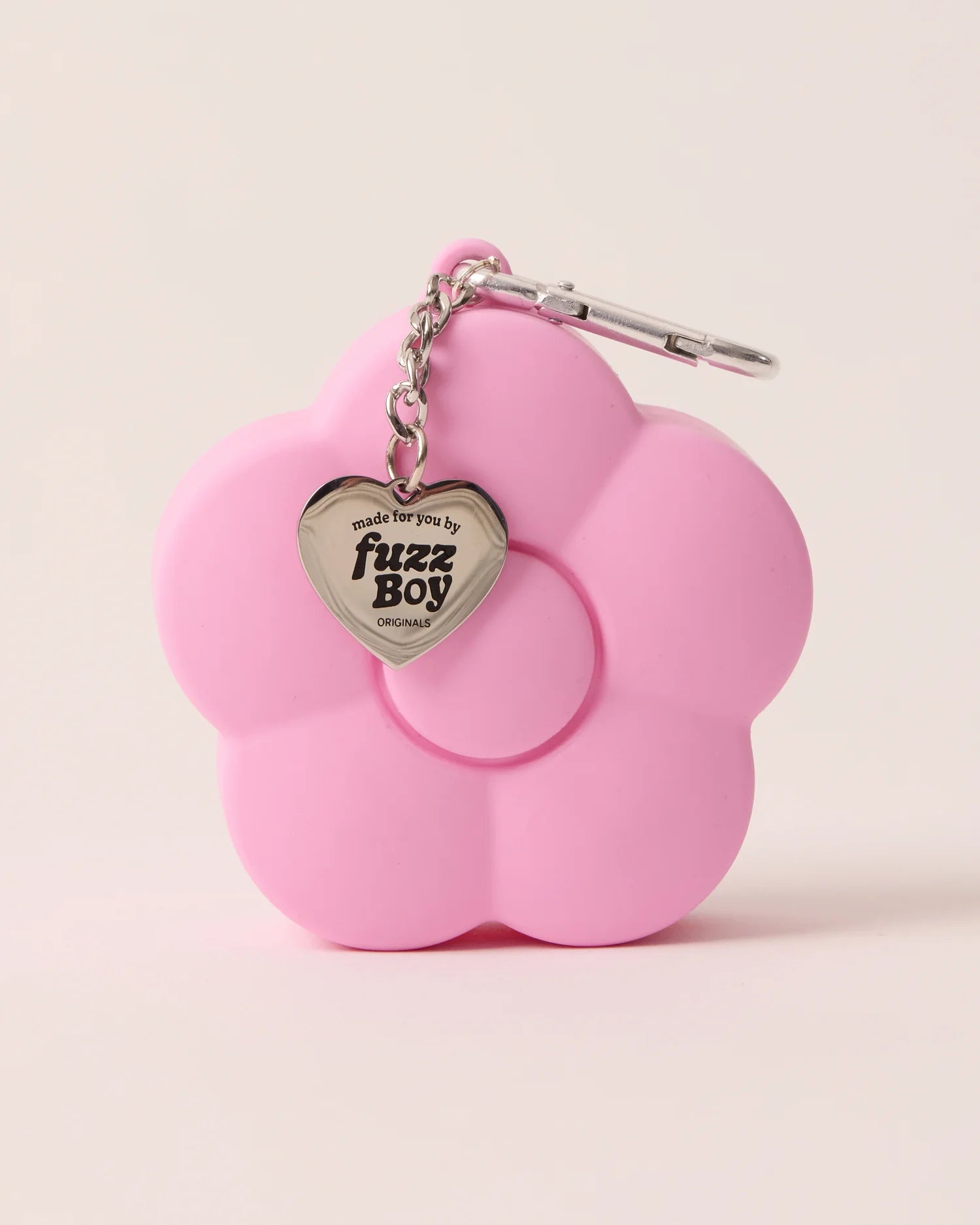 Pink flower-shaped keychain with a heart-shaped tag on a beige background