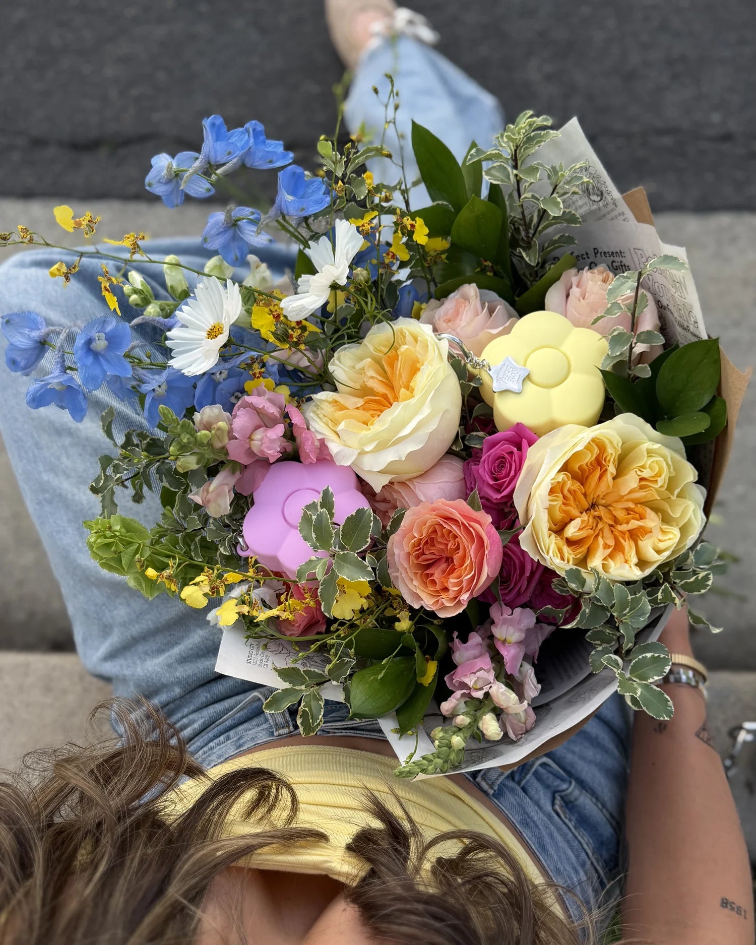Bouquet of flowers held by a person wearing blue jeans.