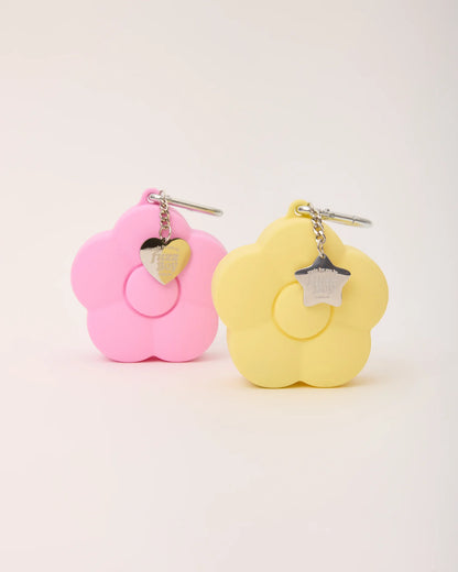 Two flower-shaped keychains, one pink and one yellow, on a light beige background.