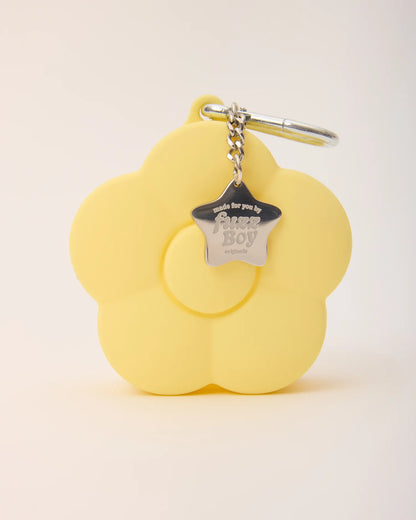 Yellow flower-shaped keychain with a metal tag on a light beige background