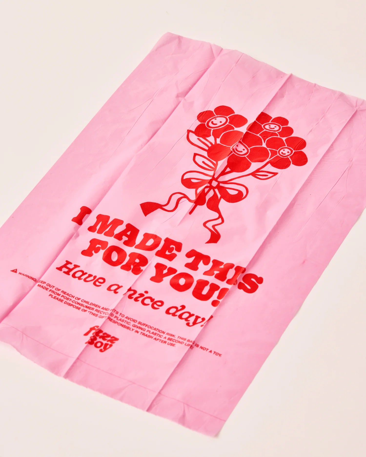 Pink bag with red floral design and text on a light beige background