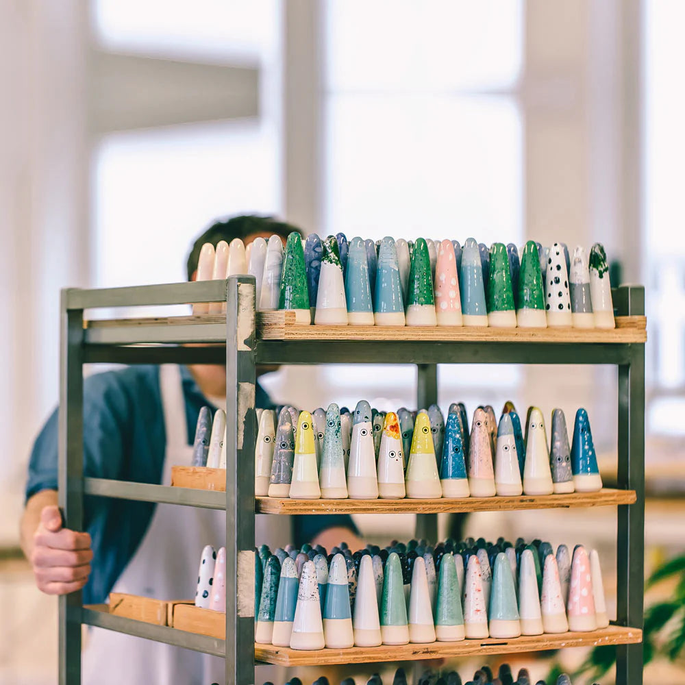 Person holding a shelf with ceramic cones of various colors and designs. Studio Arhoj Ghosts Denmark Copenhagen