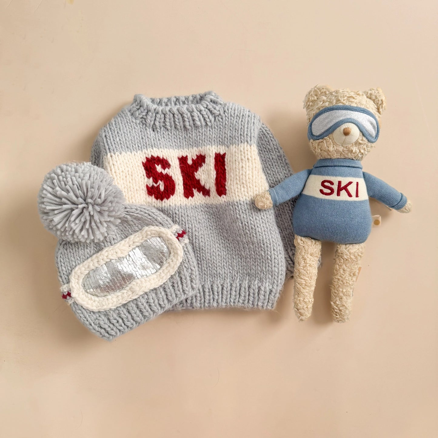 Knitted ski outfit with 'SKI' text on a beige background
