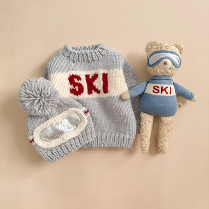 Knitted ski outfit with 'SKI' text on a beige background
