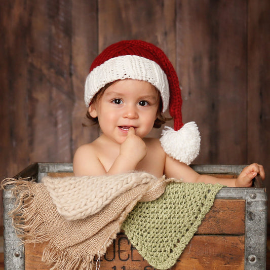 Baby wearing a red and white Santa hat in a wooden crate with a rustic background