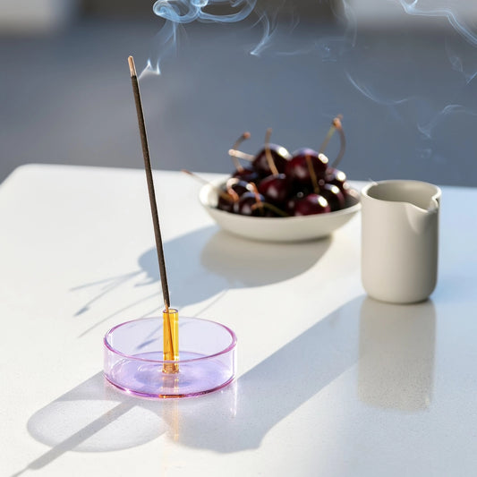 Purple and Yellow Glass Incense Holder on white table with smoke wafting off stick