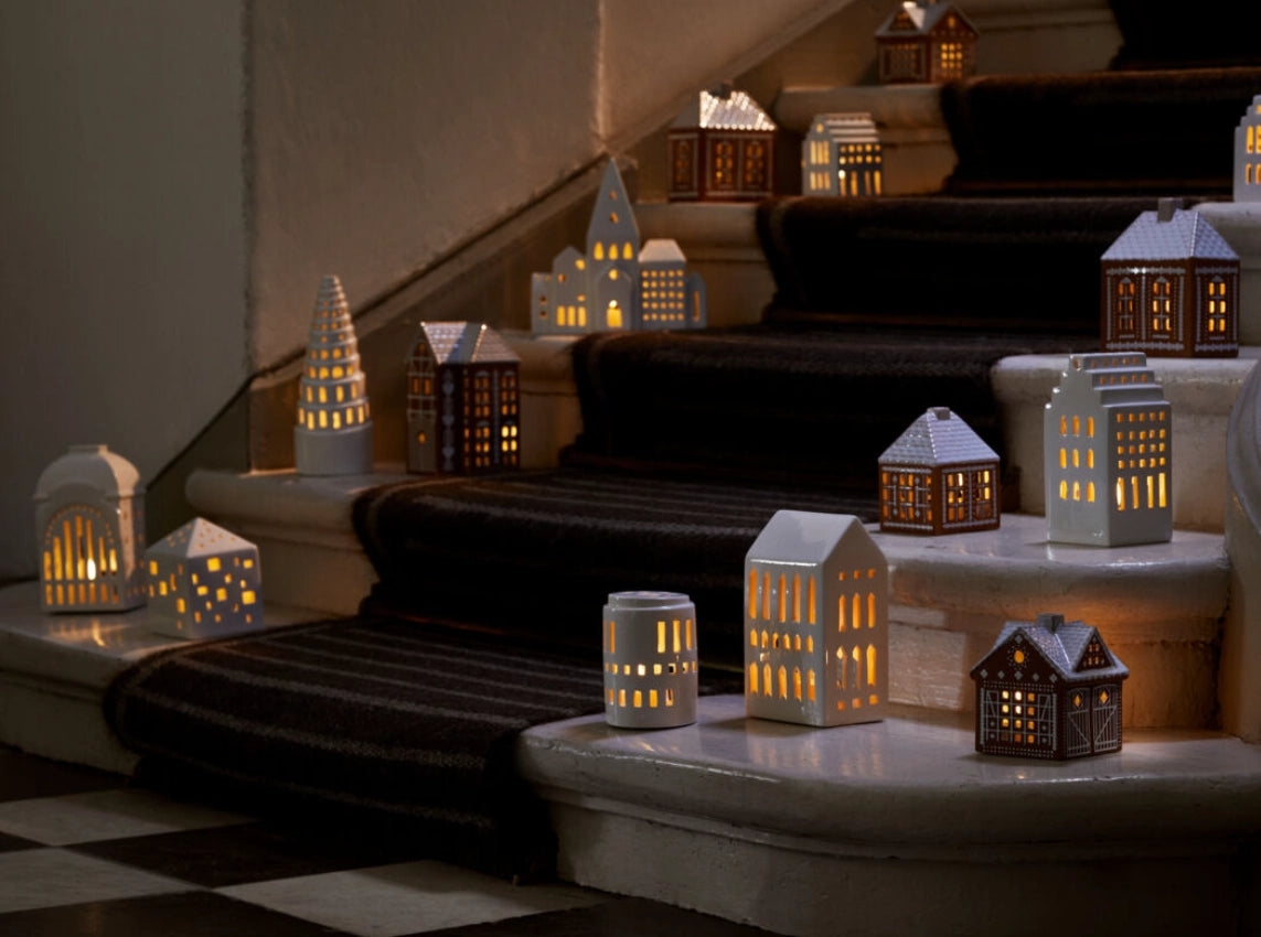 Kähler Gingerbread is a modern gingerbread house from Kähler, where the combination of a charming expression and handmade design traditions meets the warmth of the tealights creating both style and coziness on dark December evenings. The lighthouses have a brown, matte exterior similar to gingerbread dough. They are decorated with white, shiny decorations and have white roofs like frosting. As an important detail, the gingerbread houses are white glazed inside reflecting the warm light from the tealight 