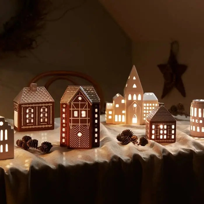 Kähler Gingerbread is a modern gingerbread house from Kähler, where the combination of a charming expression and handmade design traditions meets the warmth of the tealights creating both style and coziness on dark December evenings. The lighthouses have a brown, matte exterior similar to gingerbread dough. They are decorated with white, shiny decorations and have white roofs like frosting. As an important detail, the gingerbread houses are white glazed inside reflecting the warm light from the tealight 