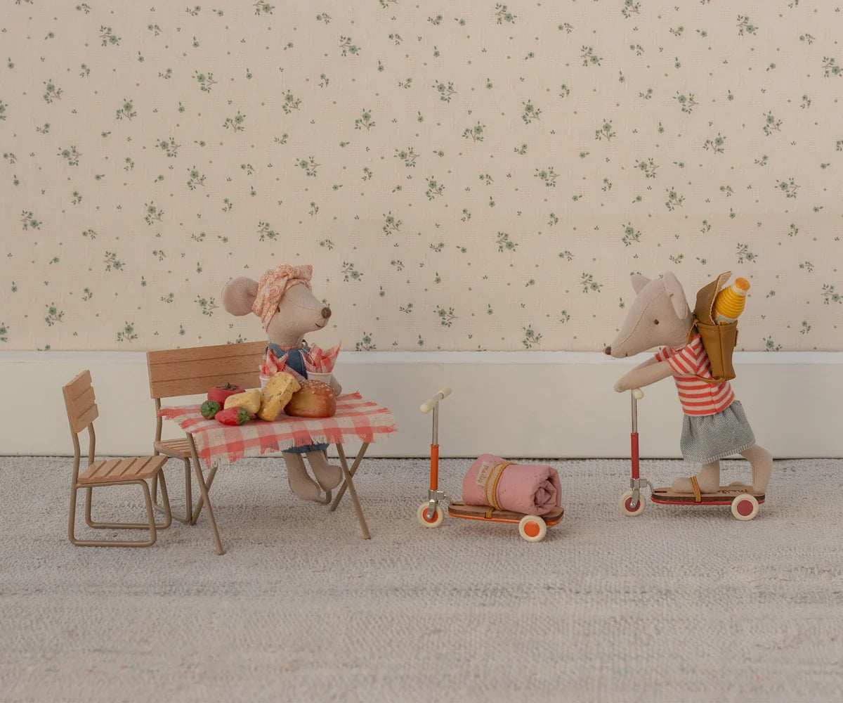 Two toy mice with a small table and chairs on a patterned floor.