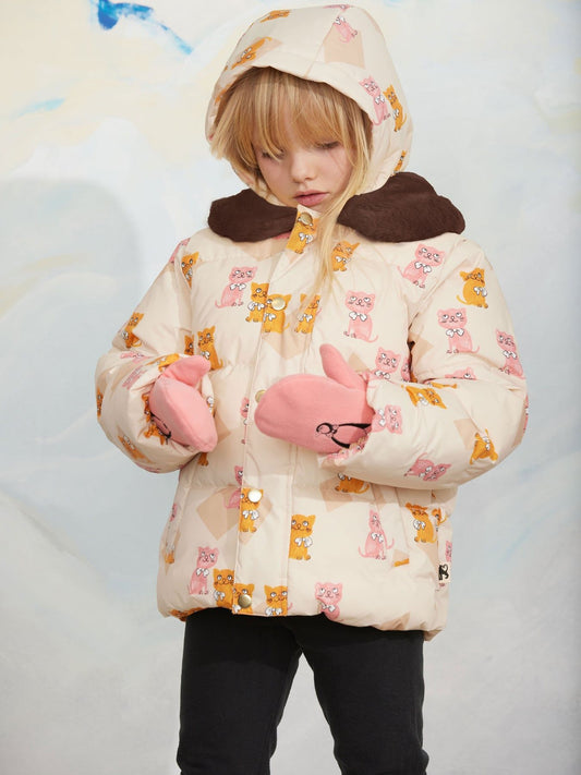 A child wearing a cream-colored hooded puffer jacket with a pink and orange cartoon animal print, a dark brown faux-fur collar, and pink mittens, standing against a light blue and white background.